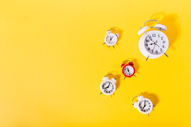 Imagen de 4 y 1 relojes de alarma rojos en pared naranja aislada,