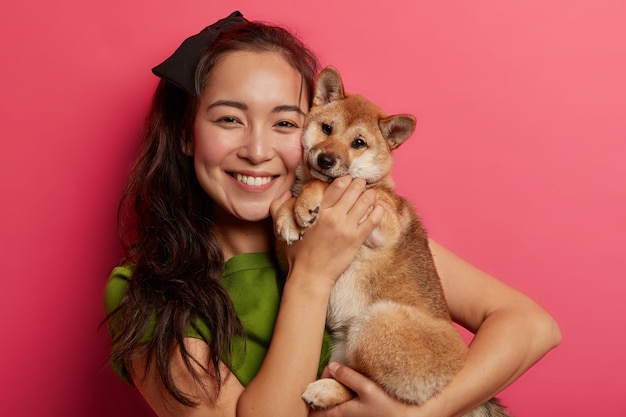 Imagen de una adorable niña con una gran sonrisa, abraza y hace una foto con un hermoso perro obediente shiba inu, disfruta jugando con un amigo de cuatro patas.