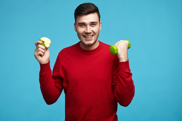 Imagen de alegre chico lindo de unos veinte años haciendo ejercicio para perder peso