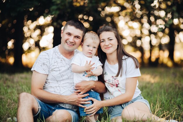 Imagen de alegre mamá caucásica, papá y su hijo se divierten juntos y sonrisas en el jardín