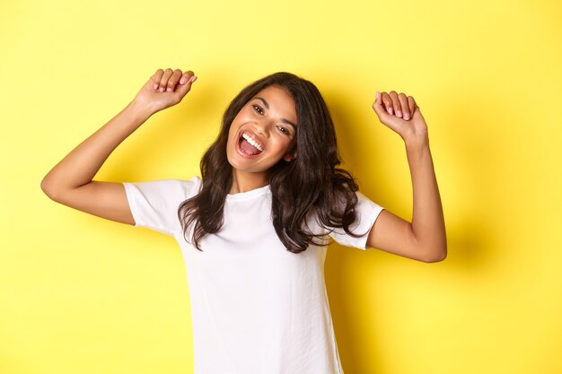 Imagen de la alegre niña afroamericana ganando luciendo feliz y celebrando la victoria triunfando