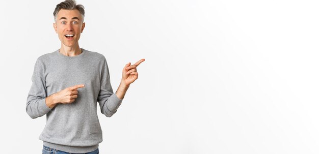 Imagen de un apuesto hombre de mediana edad sorprendido sonriendo y señalando con el dedo directamente al logotipo o a la promoción