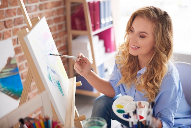 Imagen de artista femenina sentada junto al caballete