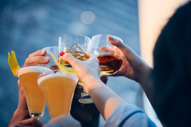 Imagen de cerca de muchas personas haciendo sonar vasos con alcohol en un brindis