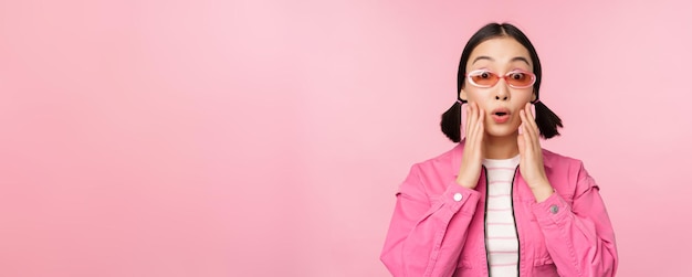 Imagen de una chica asiática que parece sorprendida y emocionada sonriendo asombrada reacción a las grandes noticias de pie sobre un fondo rosa