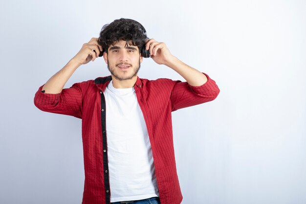 Imagen de chico joven en auriculares de pie sobre fondo blanco. Foto de alta calidad