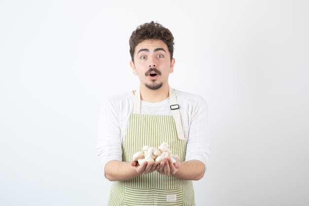 Foto gratuita imagen de cocinero macho sosteniendo champiñones crudos en blanco