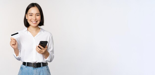 Imagen del concepto de compras en línea de una joven asiática moderna con tarjeta de crédito y compra de teléfonos inteligentes