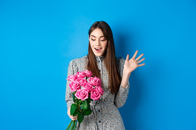 Imagen del concepto de día de san valentín de mujer joven atractiva jadeando sorprendido recibir flores sorpresa soporte ...