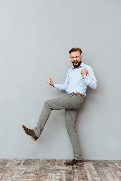 Imagen de cuerpo entero del hombre barbudo feliz gritando en ropa de negocios