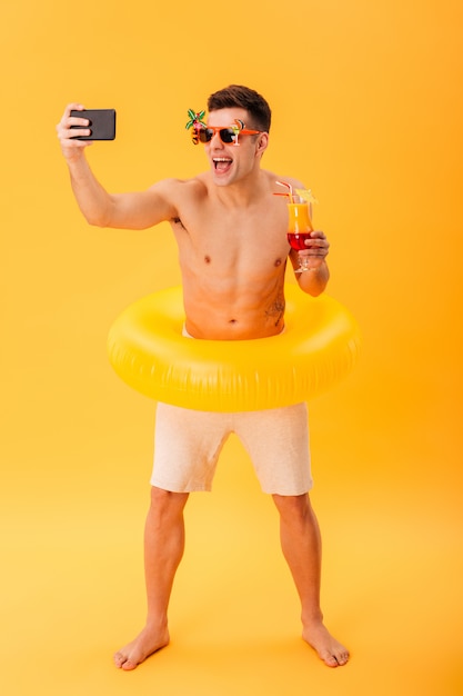 Imagen de cuerpo entero del hombre desnudo feliz en pantalones cortos y gafas de sol