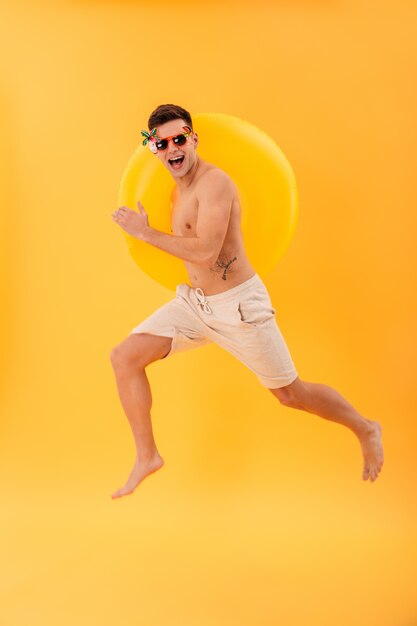 Imagen de cuerpo entero del hombre desnudo feliz en pantalones cortos y gafas de sol