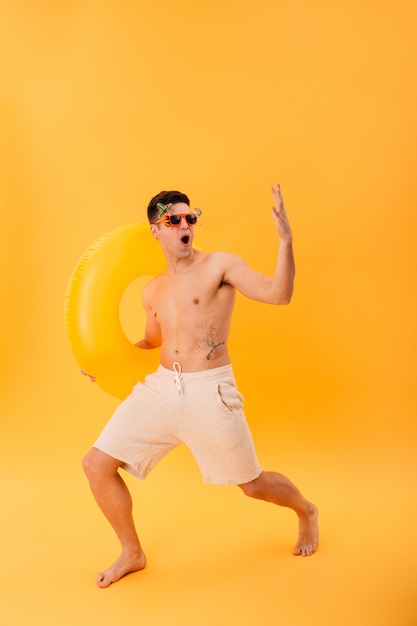 Imagen de cuerpo entero del hombre desnudo feliz en pantalones cortos y gafas de sol