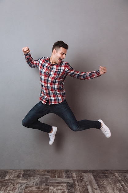 Foto gratuita imagen de cuerpo entero de hombre feliz en camisa y jeans saltando