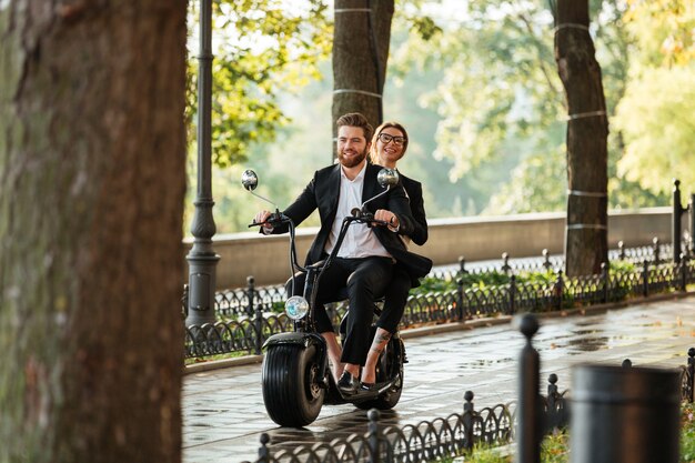 Imagen de cuerpo entero de la joven pareja elegante monta en moto