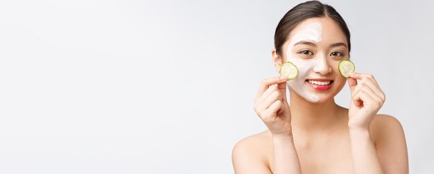 Imagen del cuidado de la piel de las mujeres asiáticas jóvenes de belleza con pepino en el estudio de fondo blanco