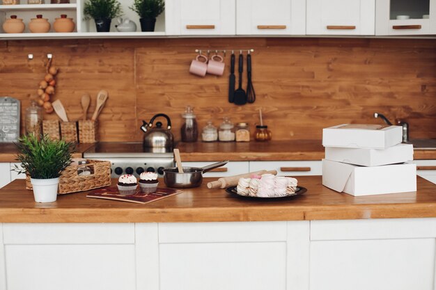Imagen de cupcakes, malvaviscos, cajas blancas con dulces en el armario