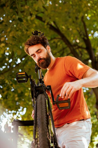 Imagen detallada de un hombre caucásico enérgico fijando y sujetando con precisión el brazo de la manivela y el pedal de la bicicleta.