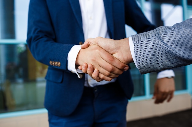 Imagen de dos jóvenes empresarios en la calle dándose la mano