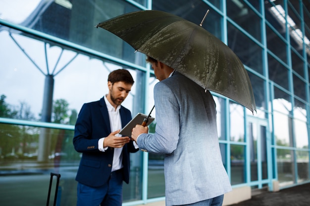 Imagen de dos jóvenes empresarios hablando en la estación de lluvias