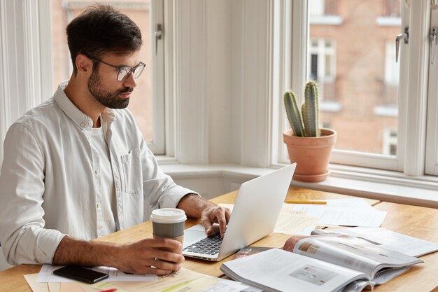 Imagen de un empresario sin afeitar concentrado observa un seminario web importante o una conferencia en línea