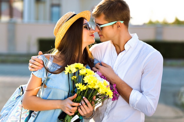 Foto gratuita imagen de estilo de vida al aire libre de una pareja feliz enamorada divirtiéndose y volviéndose locos juntos, abrazos y besos, cita romántica, luz del sol por la noche, calle, viajes, chicos elegantes y elegantes, amantes hermosos.