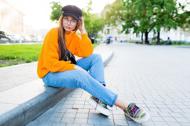 Imagen de estilo de vida al aire libre de romántica mujer soñadora sentada en la acera y disfrutando de la noche.