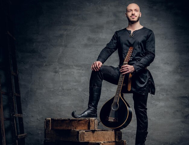 La imagen de estudio de músicos masculinos con ropa celta tradicional antigua tiene mandolina vintage.