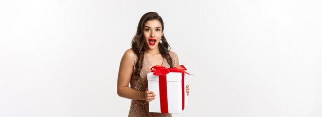 Foto gratuita imagen de feliz navidad de una mujer hermosa con un vestido glamoroso que recibe un regalo y mira a una celebridad sorprendida