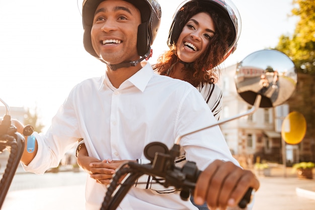 Imagen de la feliz pareja africana monta en moto moderna en la calle