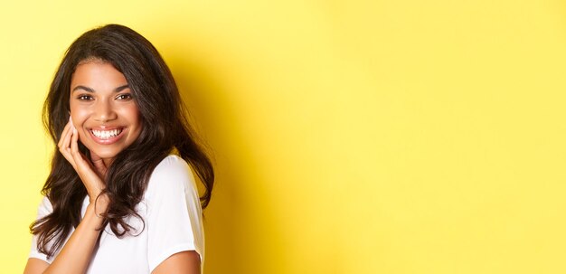 Imagen de una hermosa mujer afroamericana sonriendo coqueta y tocando la cara anunciando productos de belleza