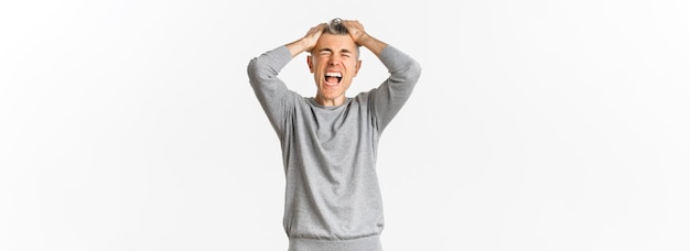 Imagen de un hombre frustrado de mediana edad entrando en pánico perdiendo algo arrancándose el pelo de la cabeza y haciendo muecas