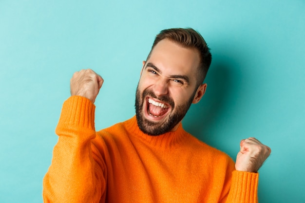 Imagen de hombre guapo aliviado sintiendo satisfacción, regocijo de ganar o logro