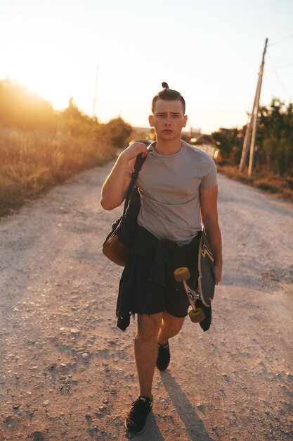 Imagen de un hombre con longboard en camino