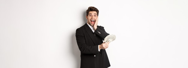 Imagen de un hombre rico y feliz con traje negro ganando un premio sosteniendo dinero y mirando emocionado a la cámara