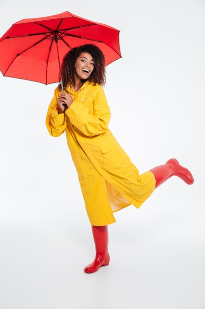 Imagen integral de alegre mujer africana en gabardina