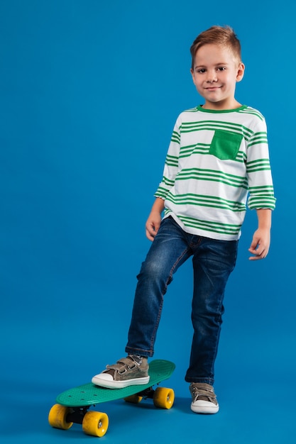 Imagen integral del joven sonriente posando con patineta