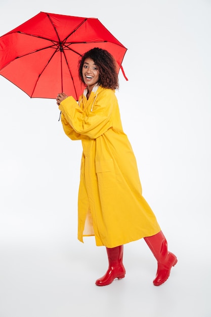 Imagen integral de sonriente mujer africana en gabardina