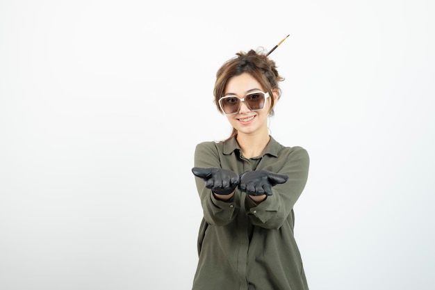 Imagen de una joven adorable con gafas y guantes negros de pie. foto de alta calidad