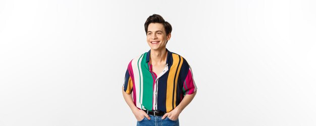 Imagen de un joven apuesto con una camiseta de verano de colores que parece feliz de pie sobre un fondo blanco
