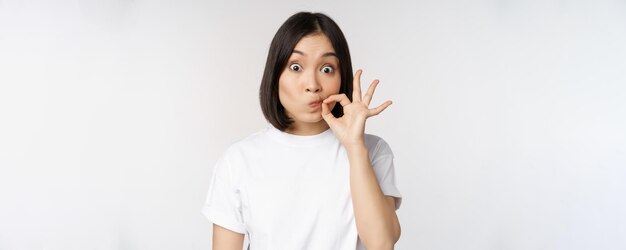 Imagen de una joven asiática que muestra un gesto de silencio que cierra la boca y los labios hacen una promesa de pie ove