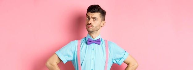 Foto gratuita imagen de un joven con bigote divertido y pajarita parado en una pose segura mirando con incredulidad