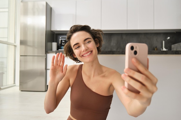 Foto gratuita la imagen de una joven bloguera de fitness graba su entrenamiento en chats en casa en línea mientras hace yoga en bri