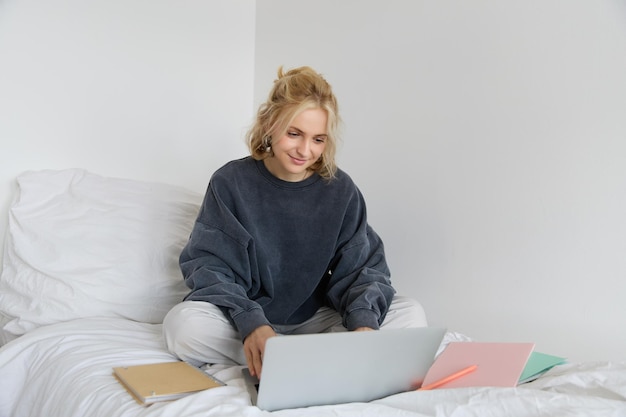 Imagen de una joven estudiante feliz que aprende desde casa conectándose a un curso en línea en su portátil
