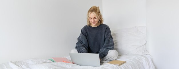 Imagen de una joven estudiante feliz que aprende desde casa conectándose a un curso en línea en su portátil