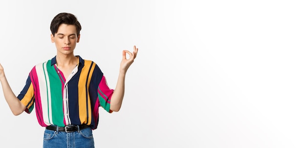 Imagen de un joven meditando tomados de la mano en gesto zen y ojos cerrados relajándose y de pie