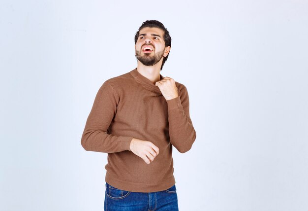 Imagen de un joven modelo de hombre sonriente de pie y posando sobre una pared blanca. Foto de alta calidad