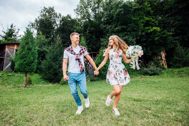 Imagen de una joven pareja cogidos de la mano y corriendo por el parque. Disfrutando de la naturaleza.