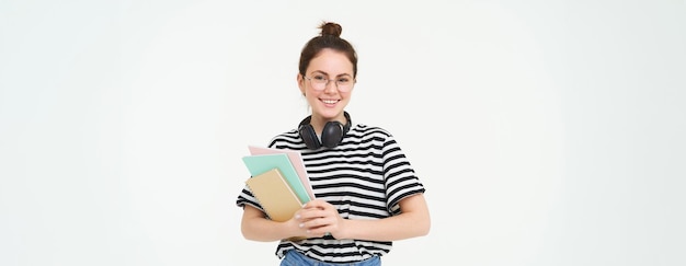 Foto gratuita imagen de una joven tutora con libros y cuadernos usando auriculares sobre su cuello aislados