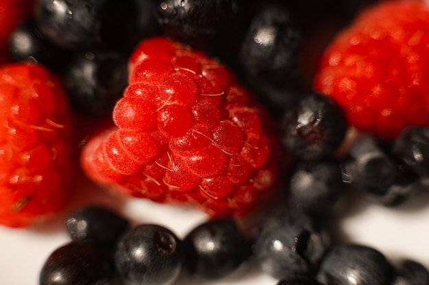 Imagen de jugosas fresas rojas maduras frescas en un plato de cerámica blanca sobre la mesa bajo la luz del sol